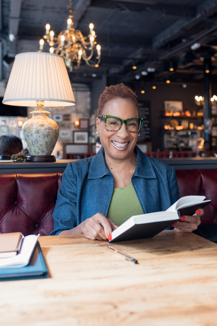 Meave Darroux smiling at a table with an open book
