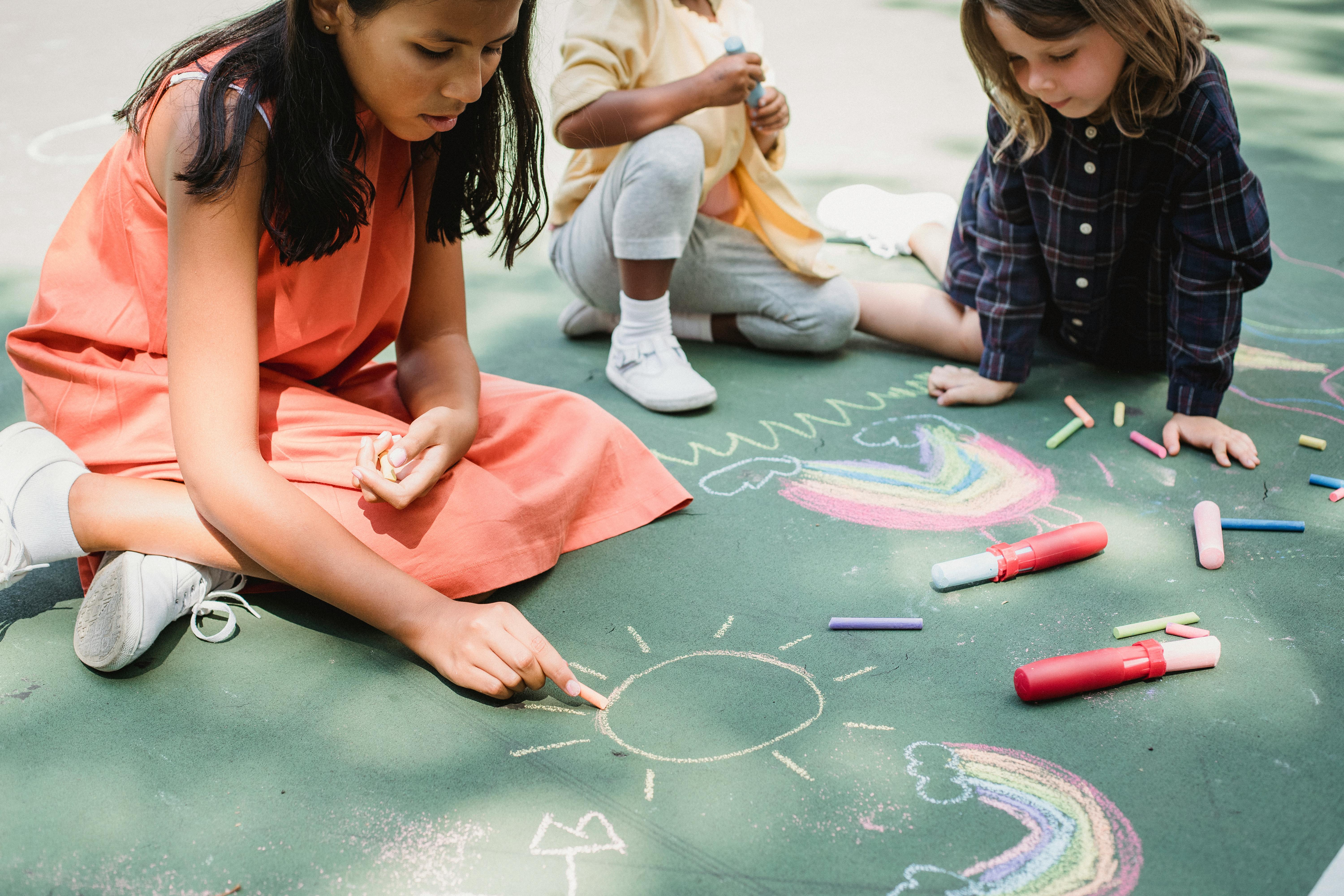 Diverse children drawing with chalk in a playground